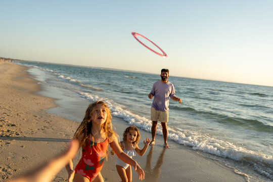 A family playing frisbee on the beach at golden time.