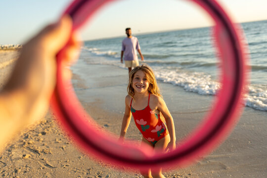 A family playing frisbee on the beach at golden time.