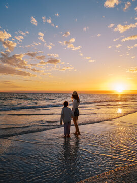 Mom and daughter on beach at sunset