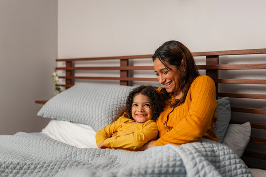 Mother and daughter smiling in bed