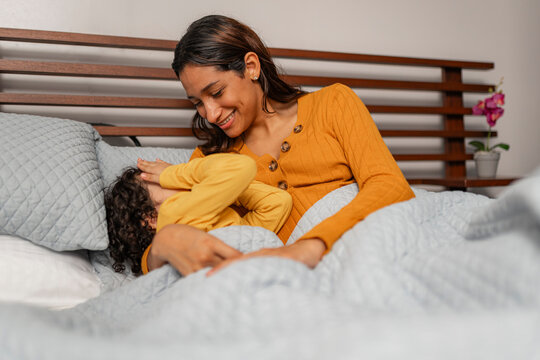 Mother and daughter playing in bed