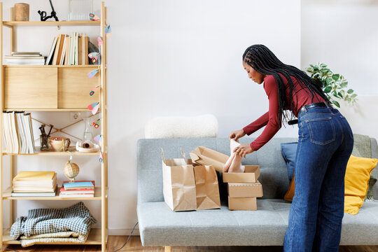 Woman at home unboxing recent purchases on the sofa