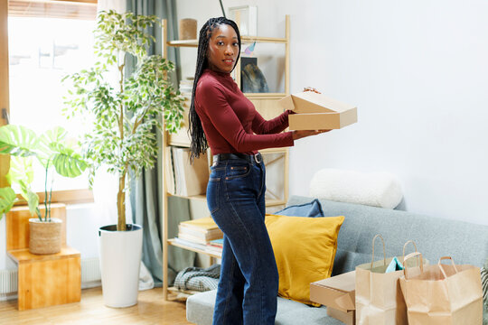 Woman at home organizing shopping bags and boxes on the sofa
