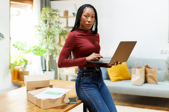Woman entrepreneur organizing packages to deliver looking at camera