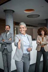 Businesswoman extending hand for handshake in office lobby