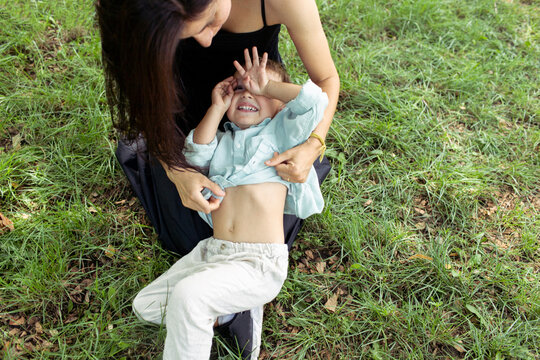 mother and son are sitting on the grass and laughing