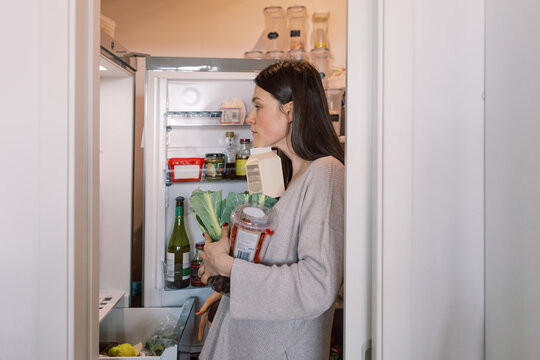 Young Woman Organizing Groceries in Refrigerator