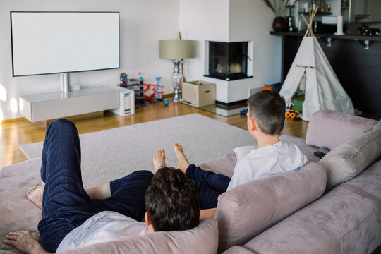 Father and son relaxing on the couch watching TV