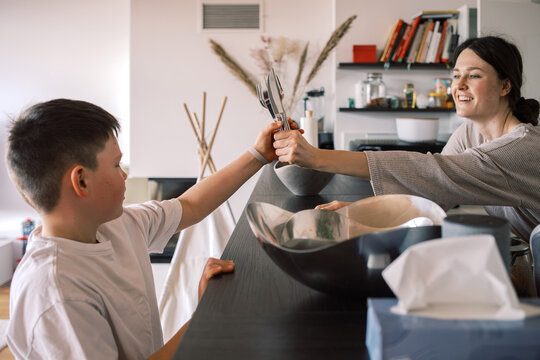 Child Takes utensils from Mom in Modern Kitchen