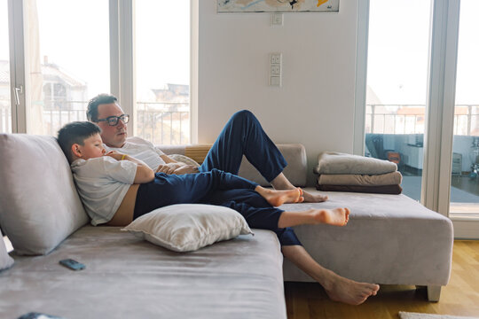 Father and son relaxing on the couch watching TV