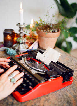 Woman Typing on a Vintage Red Typewriter in a cosy interior