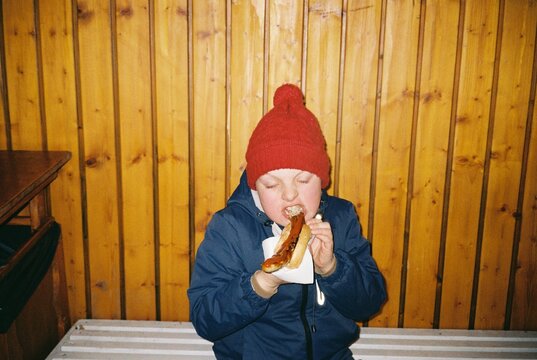 Kid Eating bratwurst in Winter Jacket 