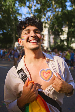 Young man showing pride heart on this chest during pride parade