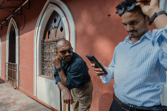 Two Men Waiting with Luggage Outside Building