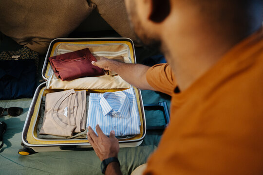 Man Organizing Clothes in Suitcase