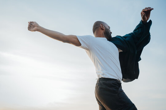 Man Joyfully Dancing Outdoors at Sunset With Open Arms