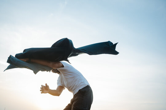 Man Running With a Jacket Under a Bright Sky at Sunset