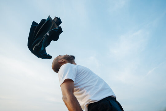 Man Throws Jacket Into the Sky During Sunset at an Outdoor Location