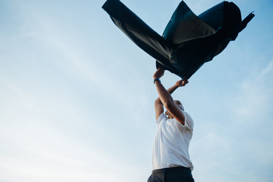 Man Joyfully Tosses Coat Into the Air on a Sunny Day