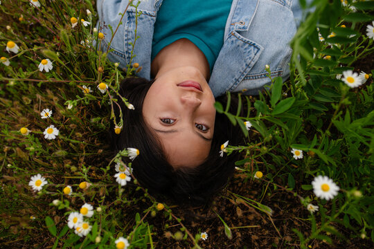 Little girl lying smiling on a grassy field with wild flowers.