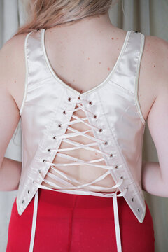 Elegant back lacing design of a satin top worn by a model 