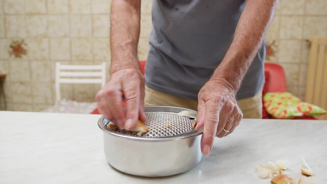 Hands of a man grate hard bread to make crumbs food