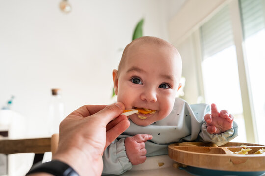 Parent feeding smiling baby