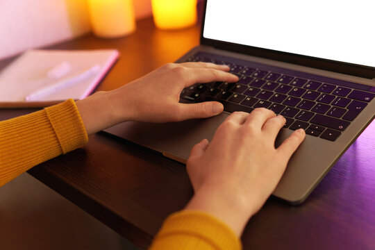 Person typing on laptop with warm lighting in a cozy indoor workspace.