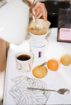 Brewing coffee with fresh oranges on a white countertop
