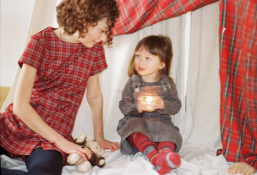 Cozy indoor moment between mother and daughter in a blanket 