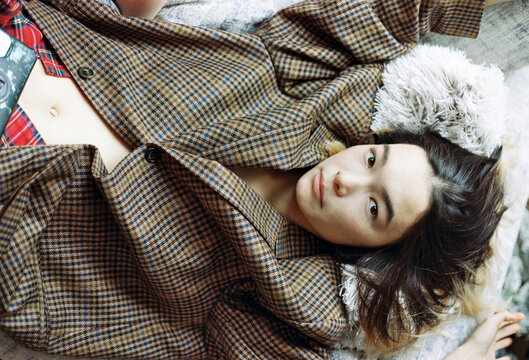 Young person lounging on a cozy surface while wearing a checked jacket