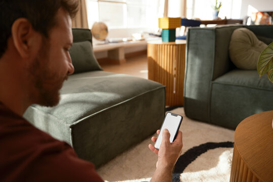 Anonymous man texting on phone with blank screen .