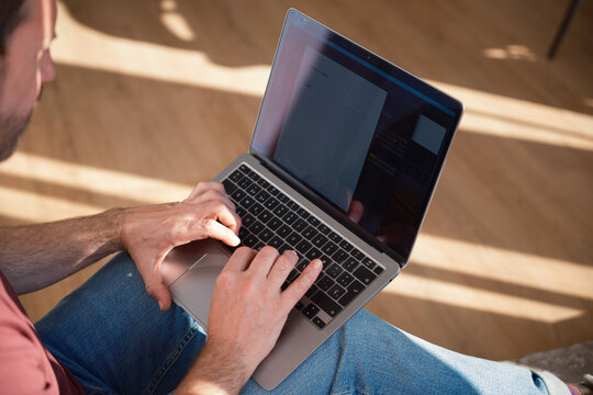 Crop of anonymous man using laptop indoors