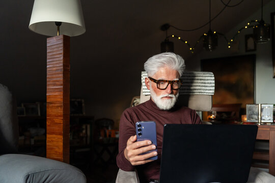 Senior Man Using Smartphone and Laptop