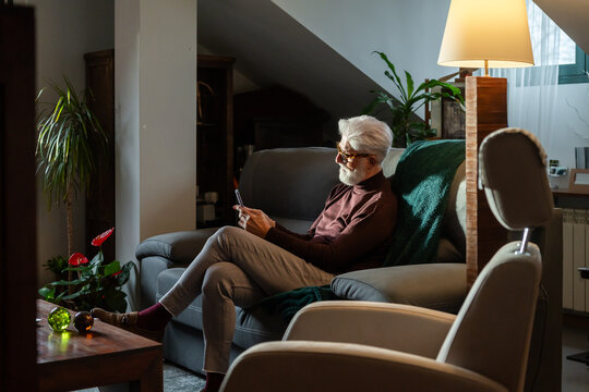Senior Man Relaxing with Smartphone at Home