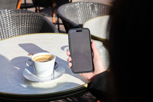 Person sitting at cafe table holding a smartphone