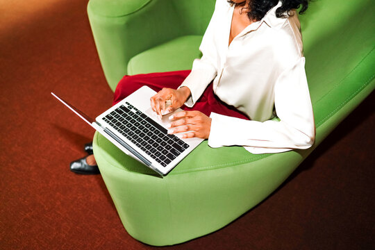 woman typing on laptop in stylish chair in modern business office