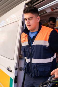 Paramedic exiting ambulance holding medical equipment