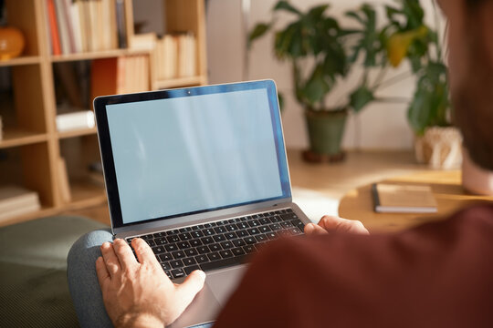 Crop of anonymous man using laptop at home