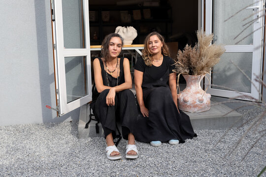two women are sitting on the steps of the house