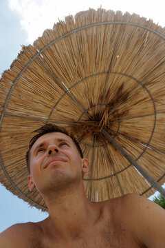 portrait of a young man under a beach umbrella