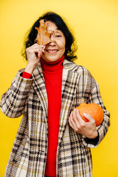 Smiling Woman Holding Pumpkin and Autumn Leaf