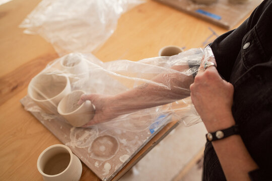 Artist uncovering drying clay pottery  
