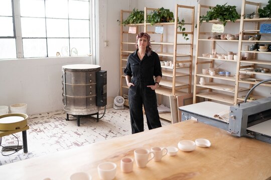 Potter Standing in Ceramics Studio with Kiln  
