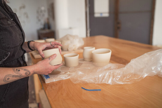 Artist inspecting handmade clay pottery  
