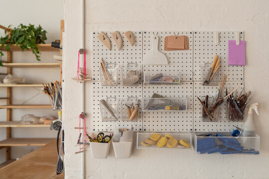 Organized pottery tools on pegboard wall  
