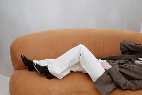 Anonymous woman lying on sofa in trendy outfit