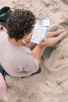 Artist Writing on a Watercolor Postcard While Sitting on the Beach