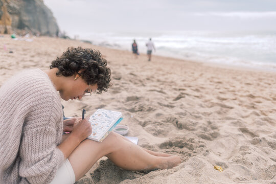 Artist Writing on a Watercolor Postcard While Sitting on the Beach
