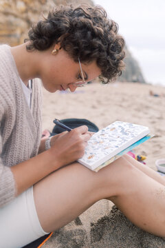 Artist Writing on a Watercolor Postcard While Sitting on the Beach